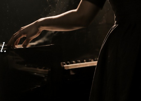 Close-up of a pianist at a grand piano in warm stage light